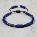 Gros plan d'un bracelet homme en bâtonnets de lapis-lazuli et séparateurs hématite sur fond pierre claire