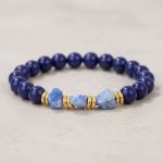 Gros plan d'un bracelet homme en lapis-lazuli poli et pierres brutes avec rondelles dorées sur fond pierre claire
