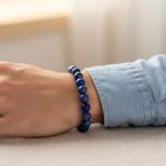 Poignet d'un homme portant un bracelet élastique en grosses perles de lapis-lazuli bleu