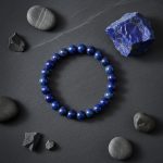Bracelet homme en perles de lapis-lazuli présenté sur ardoise avec lapis-lazuli brut