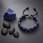 Bracelet homme en plaques de lapis-lazuli tissé macramé présenté sur ardoise avec lapis-lazuli brut