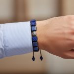 Poignet d'un homme portant un bracelet en plaques de lapis-lazuli tissé macramé avec cordon ajustable