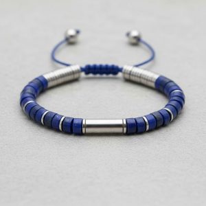 Gros plan d'un bracelet homme en rondelles de lapis-lazuli bleu et séparateurs acier sur fond pierre claire