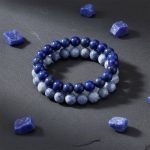 Bracelet homme en rondelles de lapis-lazuli et acier présenté sur bois avec lapis-lazuli brut