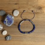 Bracelet homme en rondelles de lapis-lazuli et acier présenté sur bois avec lapis-lazuli brut