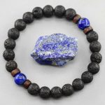 Gros plan d'un bracelet homme en pierre de lave, lapis-lazuli et perles de bois avec pierre brute sur fond clair