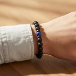Poignet d'un homme portant un bracelet élastique en pierre de lave, lapis-lazuli bleu et perles de bois