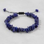 Gros plan d'un bracelet en chips de lapis-lazuli bleu moucheté de pyrite sur fond pierre claire