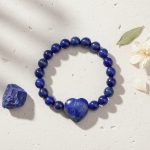 Bracelet en lapis-lazuli avec cœur central présenté sur pierre claire avec cristal de lapis