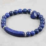 Gros plan d'un bracelet en lapis-lazuli avec cœur et barre incurvée sur fond clair