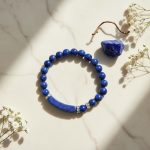 Bracelet en lapis-lazuli avec cœur et barre présenté sur pierre claire avec cristal de lapis