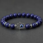 Gros plan d'un bracelet en lapis-lazuli avec main de Fatma en argent et œil bleu protecteur sur fond sombre