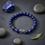 Bracelet en lapis-lazuli avec main de Fatma et œil bleu présenté sur ardoise avec pierre brute