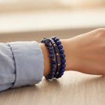 Poignet portant un ensemble de trois bracelets en lapis-lazuli de styles variés avec perles acier