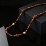 Collier perles de bois homme long détail perles bois sculptées symbole om anneaux laiton doré