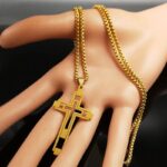 Collier croix homme acier inoxydable doré ajourée double couche présenté en main chaîne maille vénitienne
