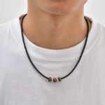 Collier cuir noir homme perles œil de tigre marron rondelles acier argenté cordon tressé porté t-shirt blanc vue de face