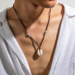 Collier homme pendentif coquillage cauri naturel cordon suede marron porte chemise blanche ouverte