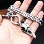 Pendentif crane de corbeau viking argent acier inoxydable tenu dans la main fond noir