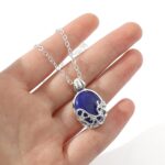 Collier homme pendentif ovale pierre bleue acier inoxydable argenté tenu en main
