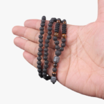 Collier homme pierre œil-de-tigre noir marron 70 cm tenu dans la main fond blanc pendentif bouddha argenté