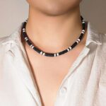 Collier ras de cou homme perles heishi noir et blanc style surf porté sur chemise blanche ouverte