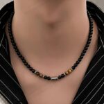 Collier œil de tigre homme perles noires onyx acier inoxydable porté sur chemise rayée