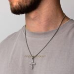 Homme barbu portant un collier pendentif croix gothique en acier inoxydable argenté chaîne maille vénitienne, t-shirt gris