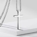 Collier pendentif croix minimaliste homme acier inoxydable argenté posé sur socle blanc