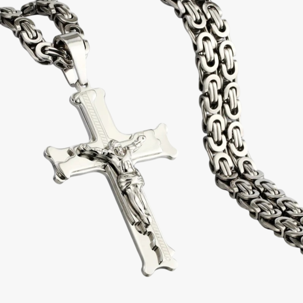 Gros plan pendentif crucifix en acier inoxydable argenté avec chaîne maille byzantine fond blanc