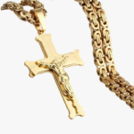 Gros plan pendentif crucifix en acier inoxydable doré avec chaîne maille byzantine fond blanc