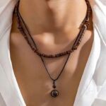 Collier pendentif homme perles bois marron oeil de tigre porté en double rang sur chemise blanche ouverte