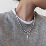 Collier perle acier inoxydable argentée pendentif noeud argente porté sur sweat gris