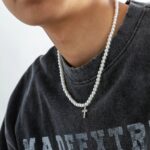 Collier perle homme blanc pendentif croix strass argentée porté sur t-shirt gris streetwear