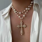 Collier perle homme pendentif croix baroque blanc doré porté sur chemise blanche