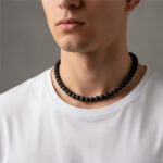 Collier perle noir homme pierre de lave ras-de-cou porté sur t-shirt blanc