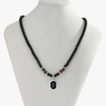 Collier ras-de-cou perlé noir homme onyx œil de tigre pendentif pierre argentée sur buste présentoir gris
