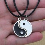 Collier yin yang couple lot 2 pendentifs émail noir et blanc cordon noir assemblés en cercle complet tenus en main