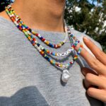 Collier perle homme multirangs perles blanches nacrées et rocaille multicolore pendentif baroque porté sur t-shirt gris